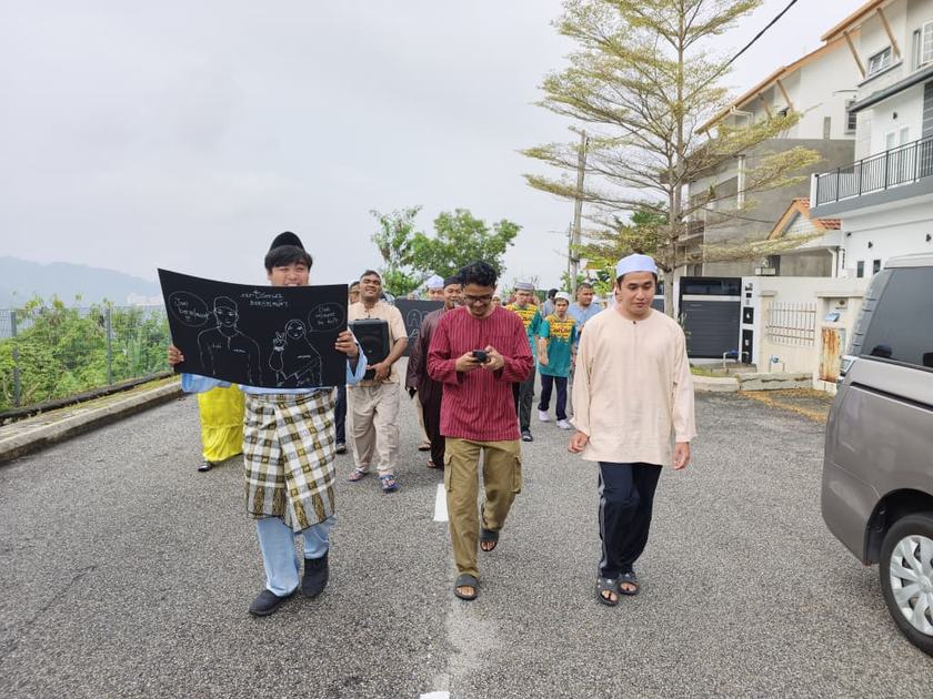 Tiga peserta perarakan berjalan di jalan kawasan Ukay Perdana.